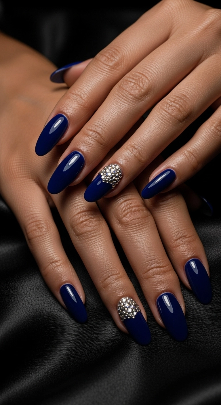 Elegant oval nails in a deep sapphire blue, accented with sparkling rhinestones.