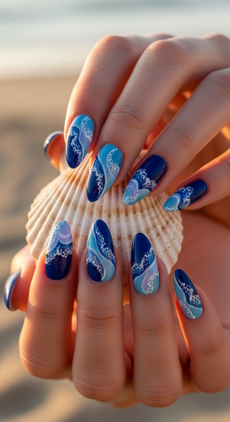 Close-up of almond-shaped nails with a glossy, blue and white ocean wave abstract design.