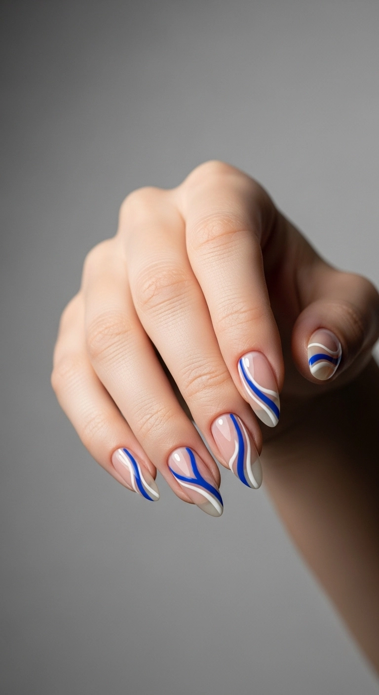 Almond nails with a chic, modern design of abstract cobalt blue and white lines on a nude base.