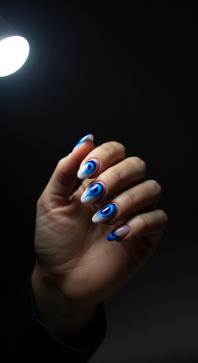 Oval nails with a sheer base and a soft, airbrushed-style cobalt blue circle in the center.