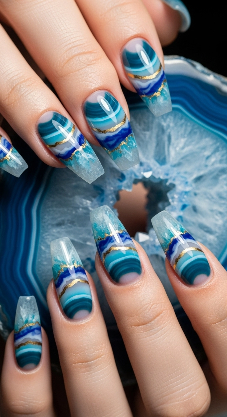 Coffin-shaped nails with a realistic blue agate geode design, featuring translucent layers and a gold center line.