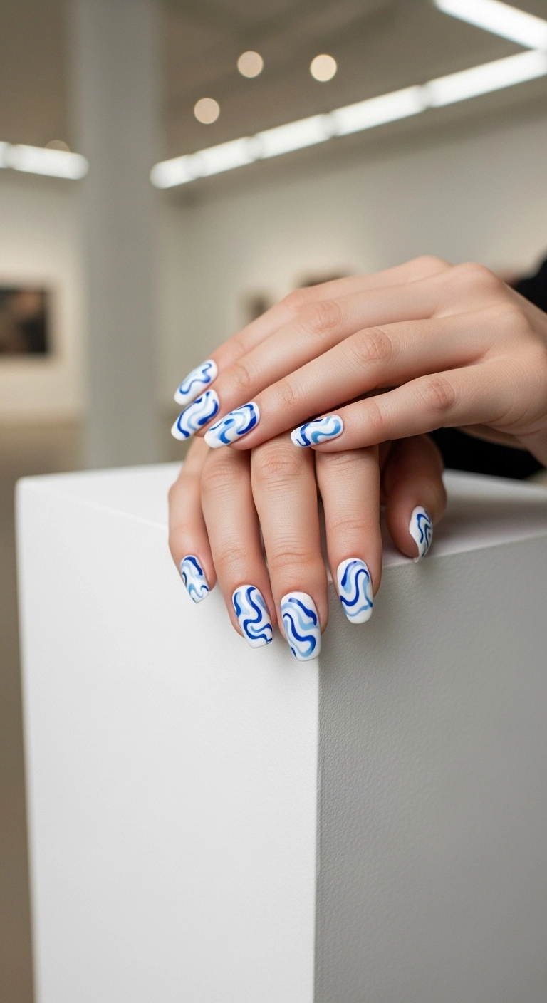 Medium squoval press-on nails with an abstract blue and white swirl design resembling liquid porcelain.
