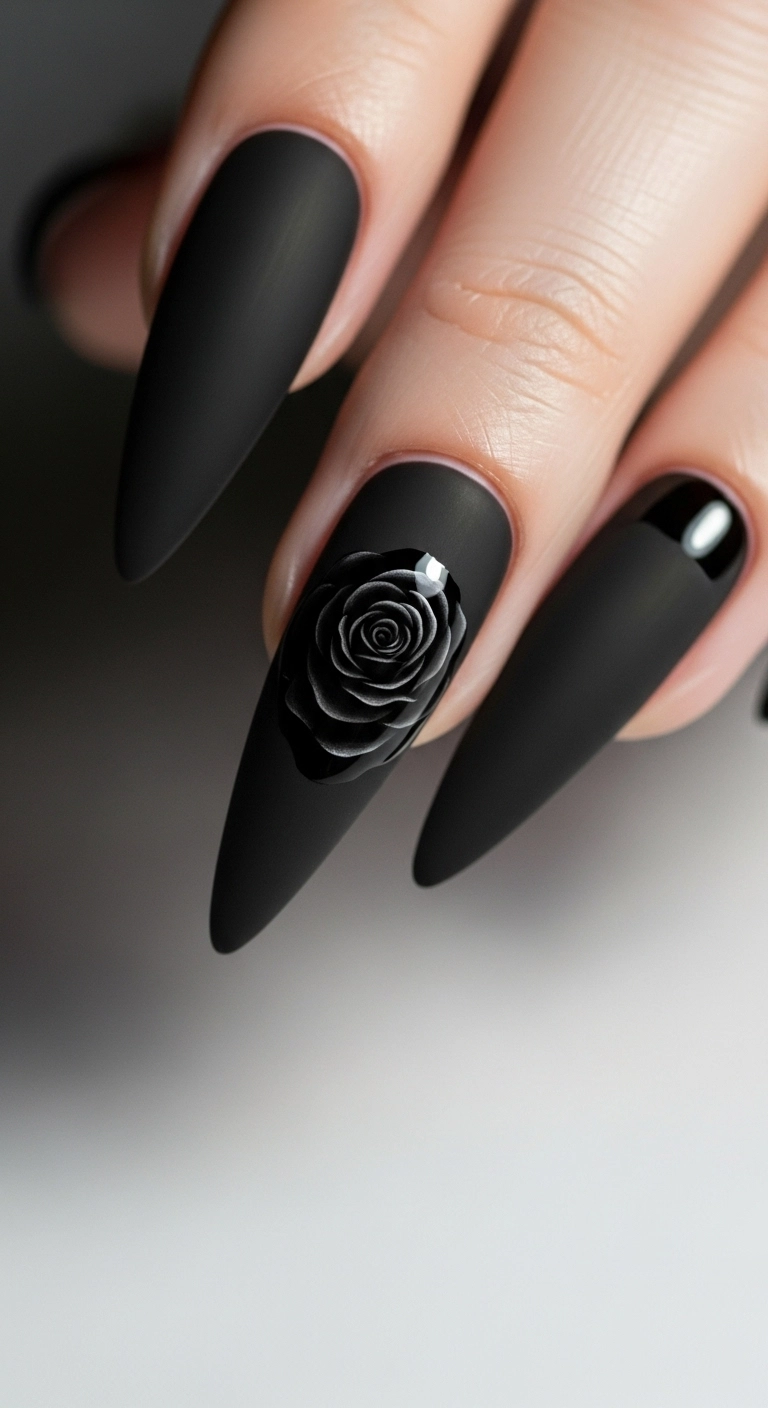 A single stiletto nail with a matte black base and a detailed glossy black rose design.