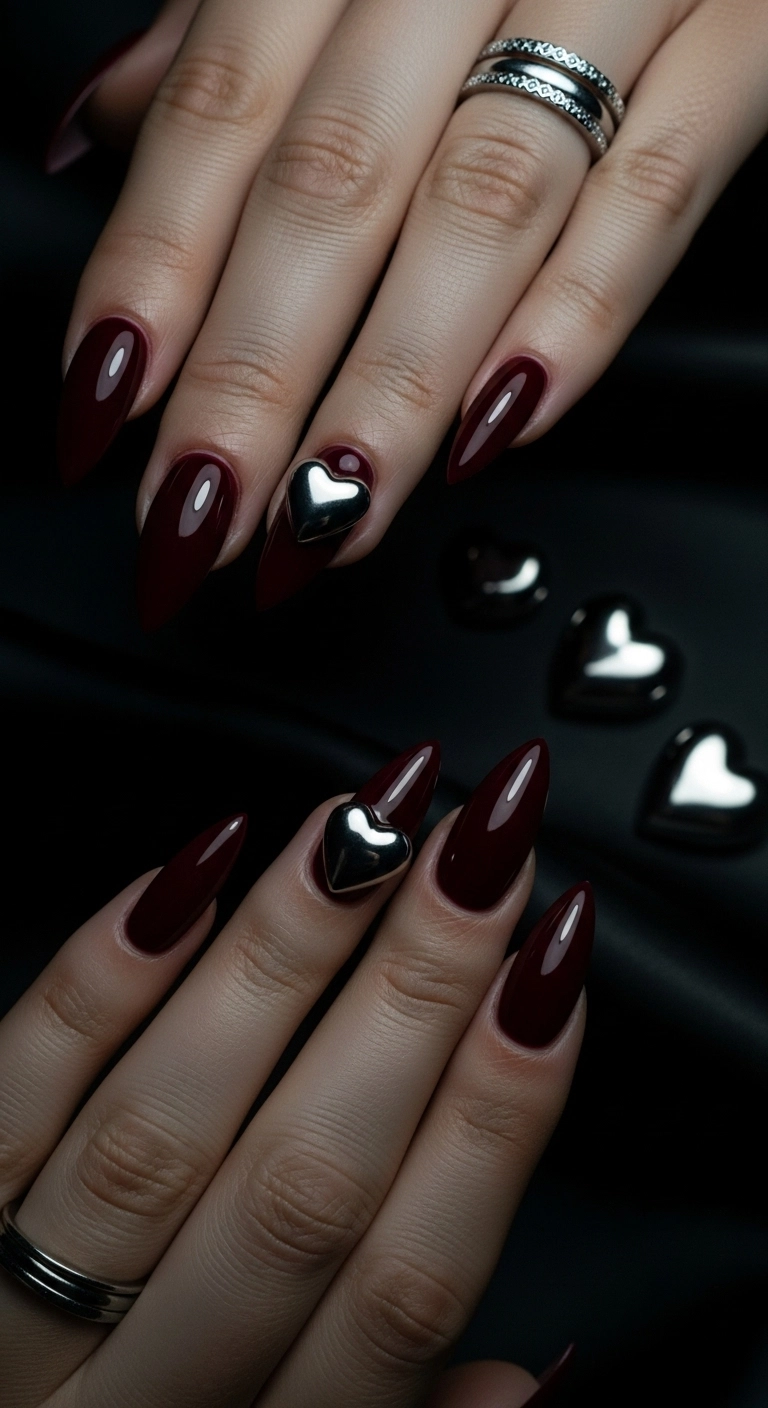 Glossy burgundy stiletto nails with a single 3D silver chrome heart on the accent finger.