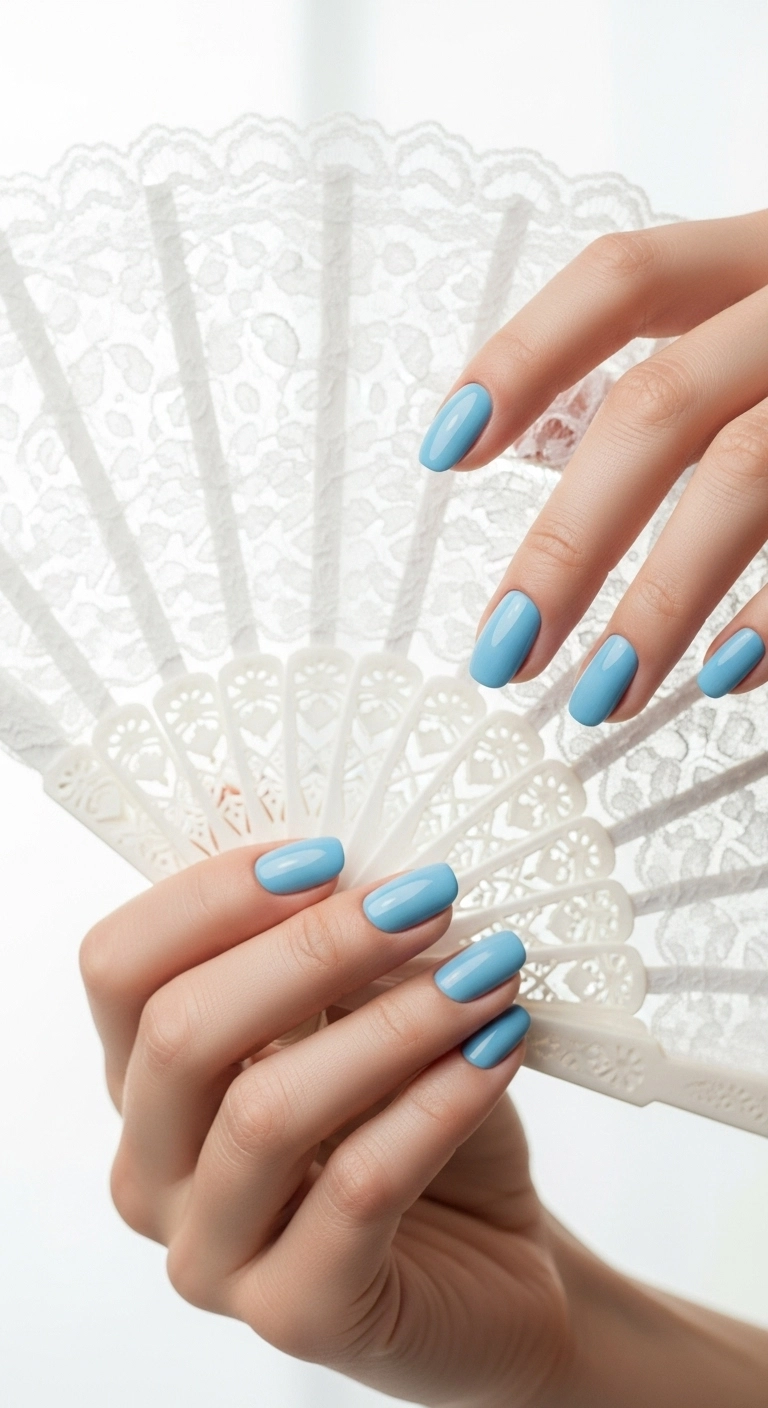 Hands with short, square-oval nails painted in a solid baby blue color.
