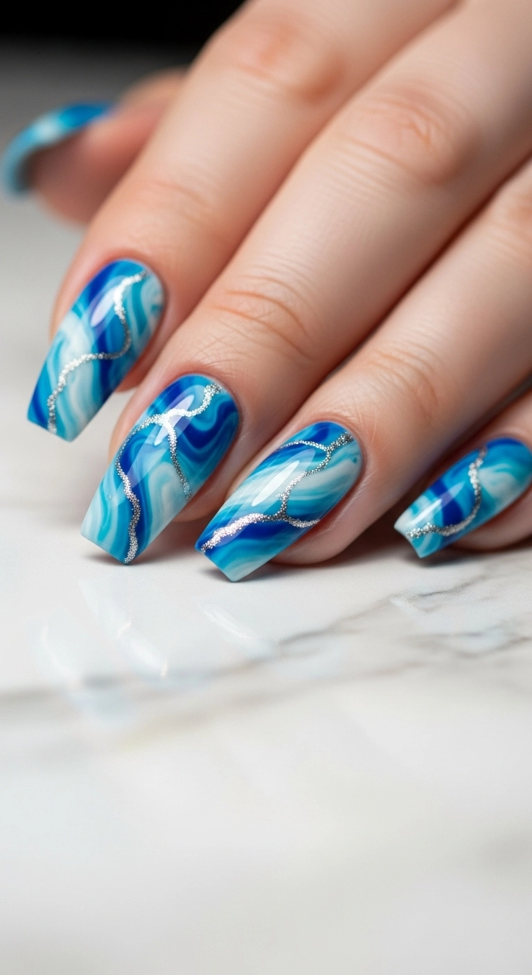 A hand with long coffin nails featuring a blue and white water marble design.