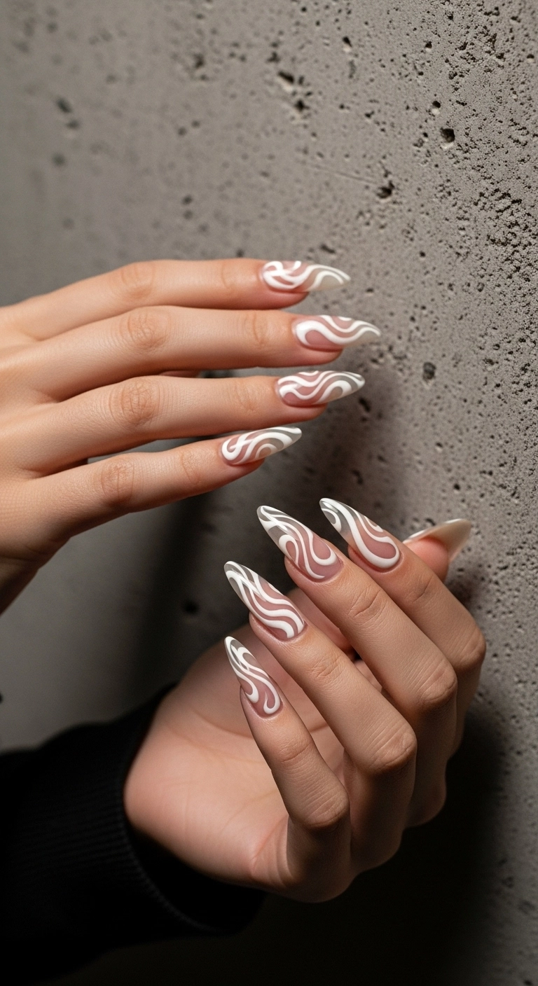 Long almond nails with a clear base and abstract white swirl designs.