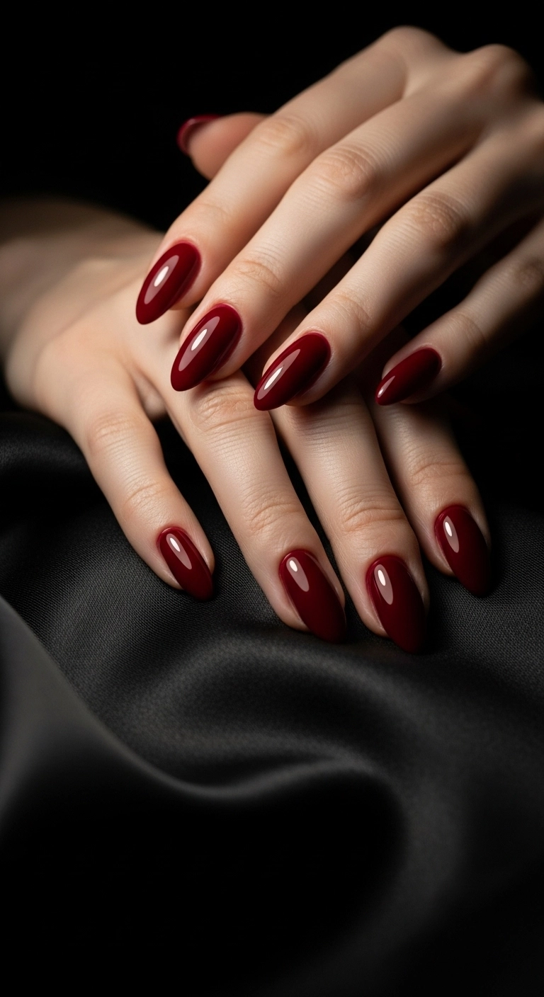 A woman's hands with classic almond-shaped acrylic nails in a deep, glossy Hollywood red.