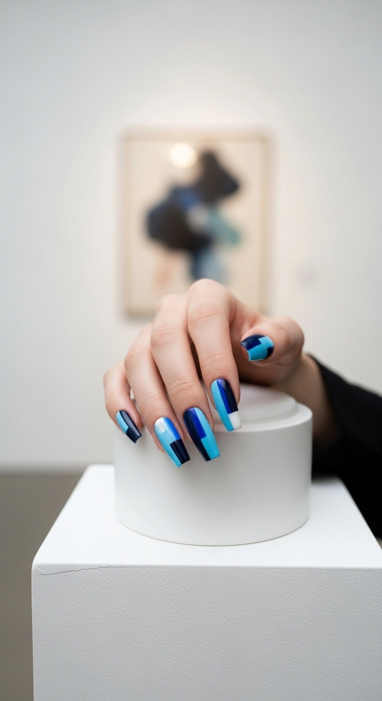 Long coffin nails with an abstract geometric pattern using shades of blue.