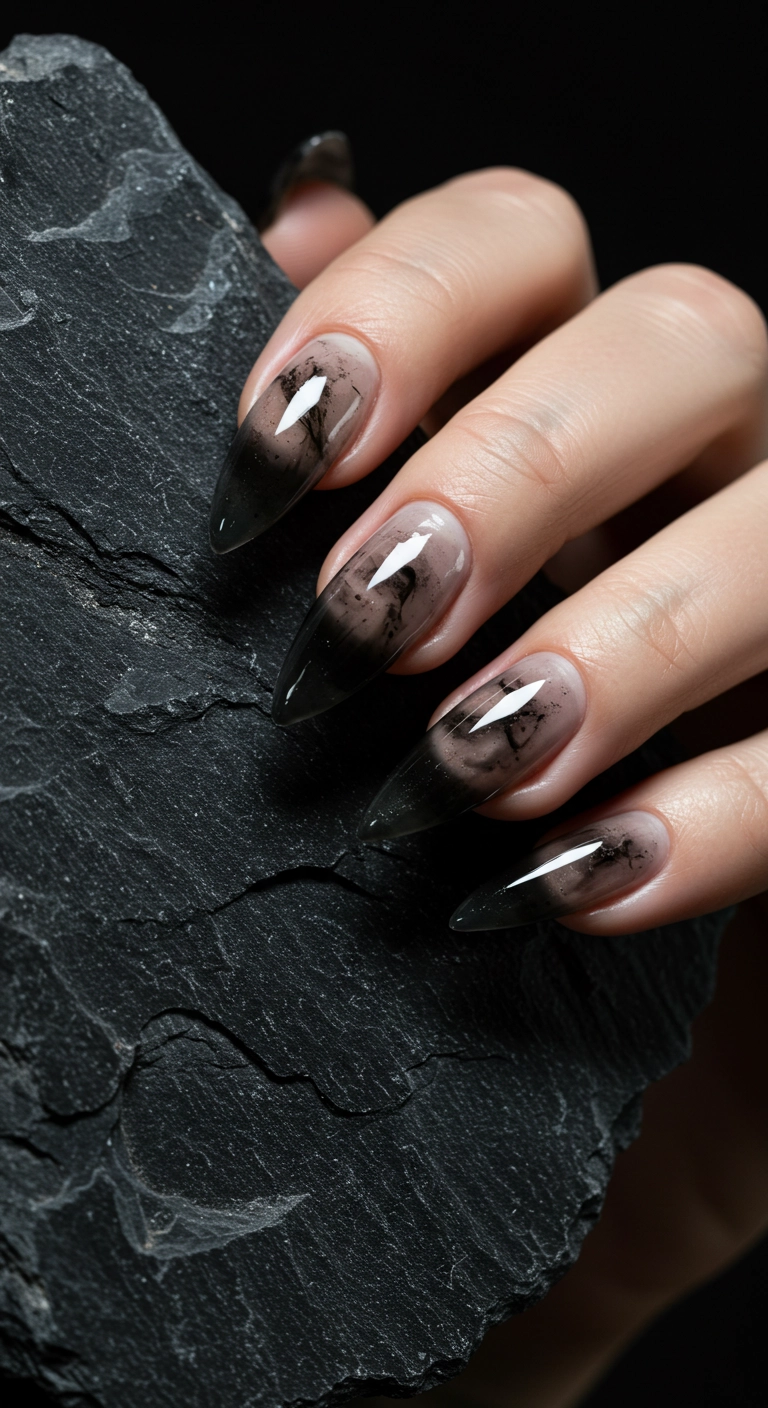 A woman's hand with long stiletto nails painted in a sheer smoky quartz black polish.