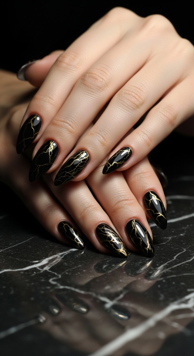 Close-up of stiletto nails with a dramatic black and gold marble art design.
