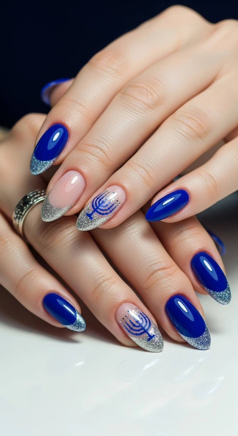 A close-up of almond-shaped nails with a royal blue base and a sparkling silver glitter French tip.