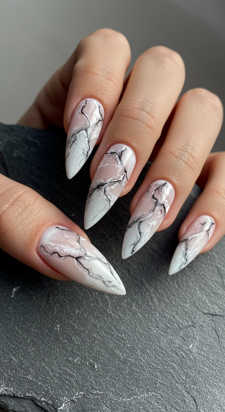 A close-up of long stiletto nails with a realistic, high-gloss white and grey marble stone design.