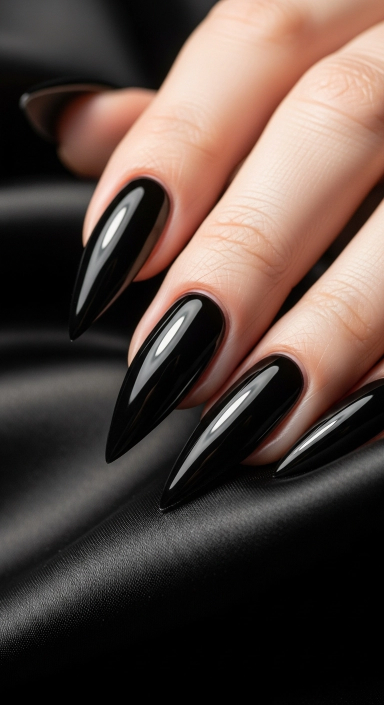 A close-up of extremely sharp, long stiletto nails painted in a high-gloss, reflective black polish.